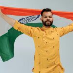 A serious man holds the Indian flag, showcasing pride and patriotism in a studio setting.